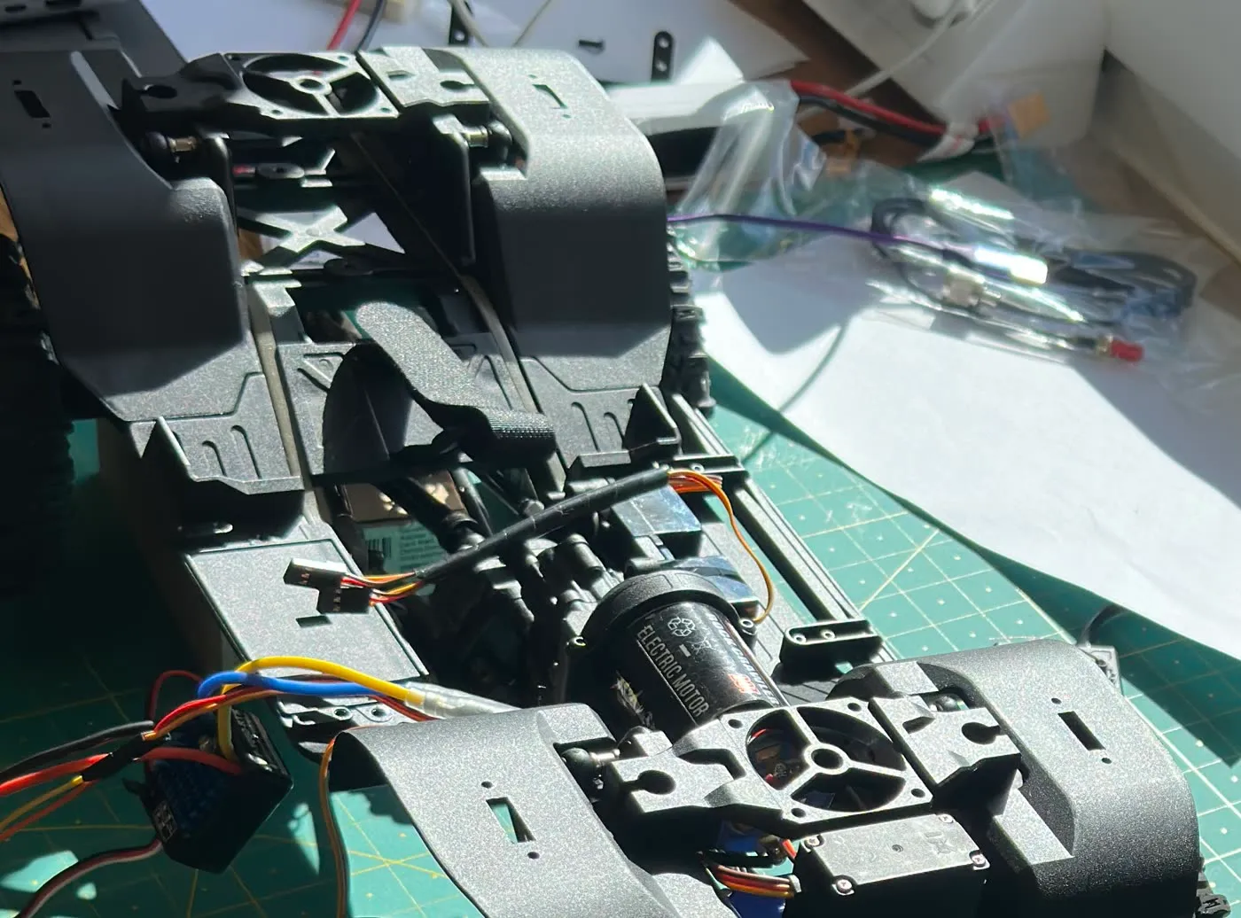 The RC crawler chassis during integration, showing the drivetrain, steering linkage and motor before the compute stack was fitted.