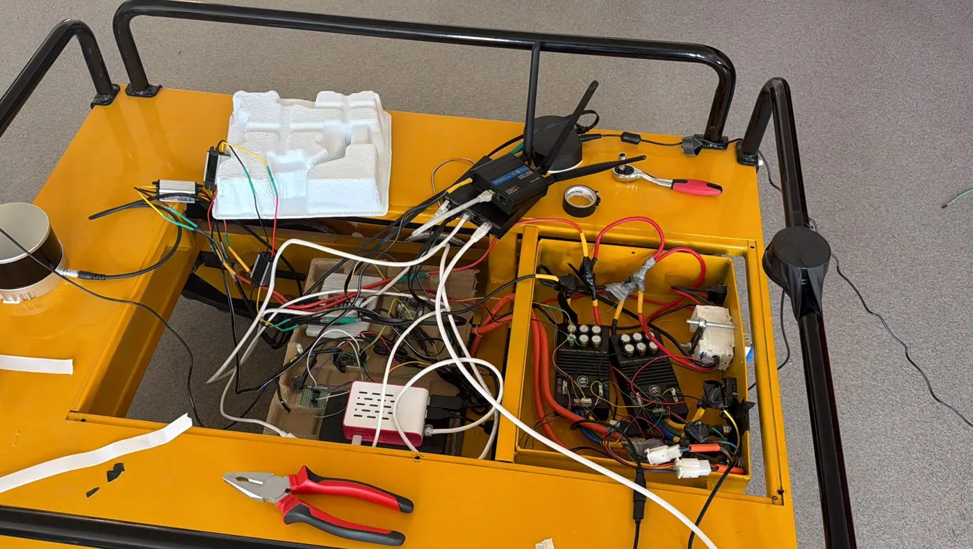 The tracked UGV's open electronics bay during integration, showing the Raspberry Pi, a network switch and the motor controllers.