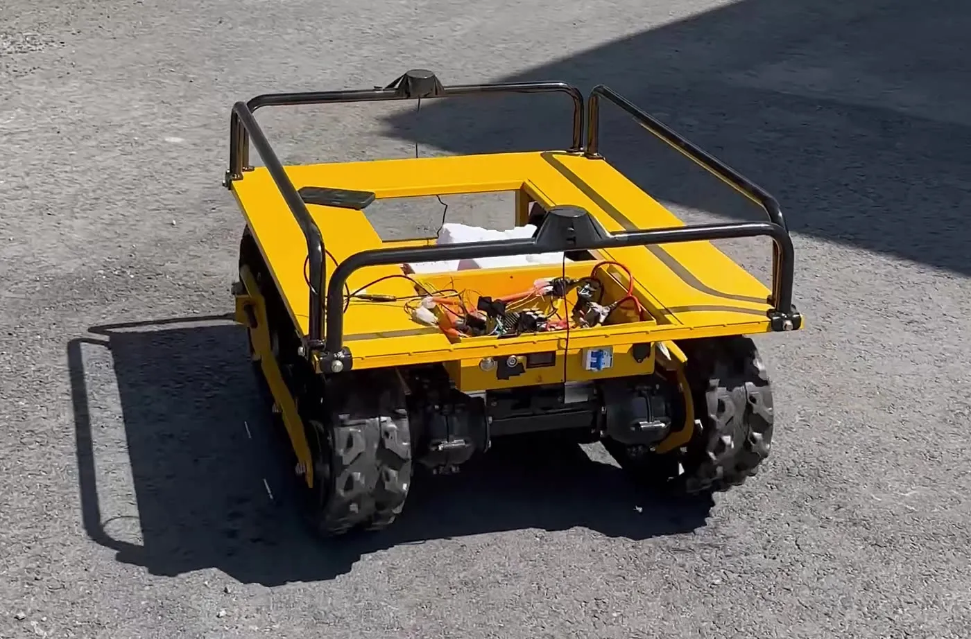 Tracked skid-steer unmanned ground vehicle outdoors, with a roof-mounted GNSS antenna mast, during an autonomous waypoint run.